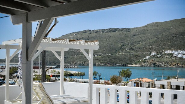 A covered outdoor seating area with a view of a coastal town and a body of water. - The Veranda of Gavrion - Premium Cycladic House (Andros)