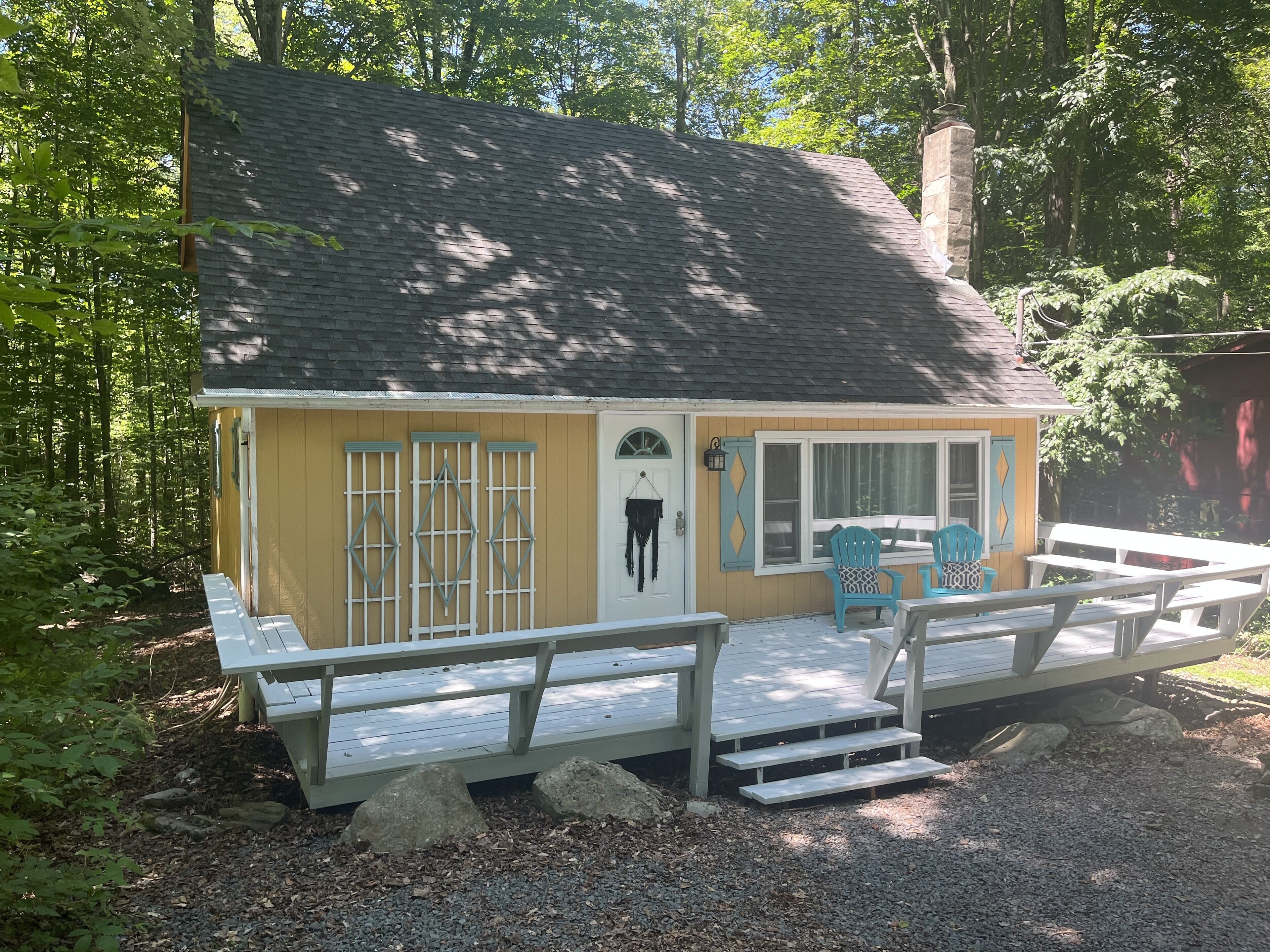 A small, single-story cabin with a porch and outdoor seating area.