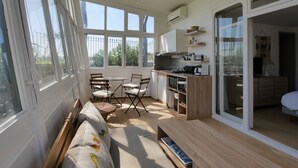 A modern kitchen with a dining area, large windows, and a sliding glass door leading to a balcony.