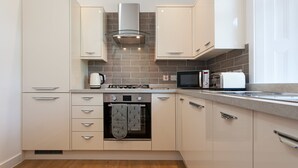 A modern kitchen with white cabinetry, a built-in oven, a microwave, and a gas stove. - The Old Manse House - Apartment (Ayr)