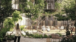 Un patio con zonas de estar, vegetación y un edificio con amplios ventanales.