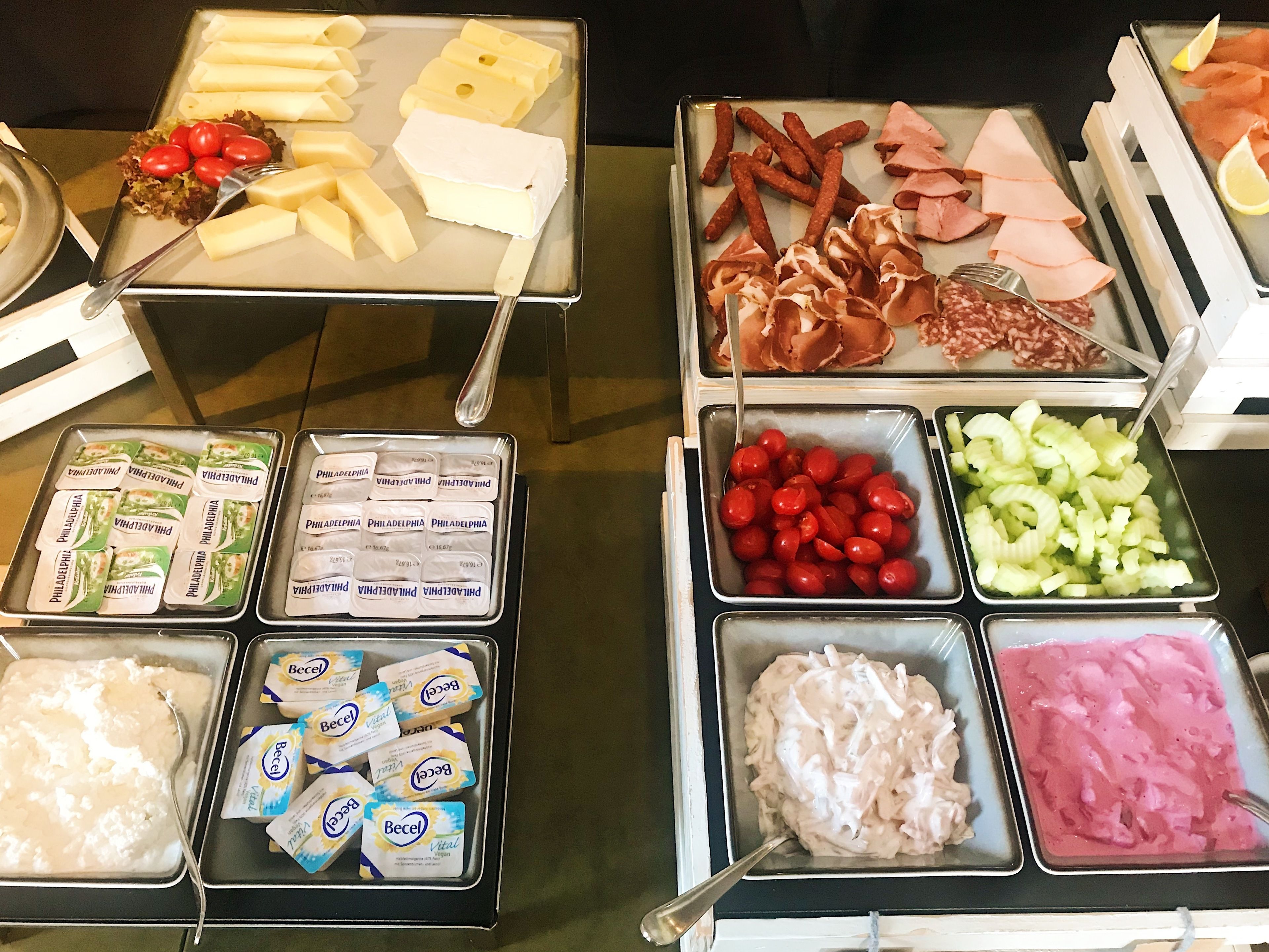 A buffet with various food items including cheese, meats, vegetables, and dairy products.