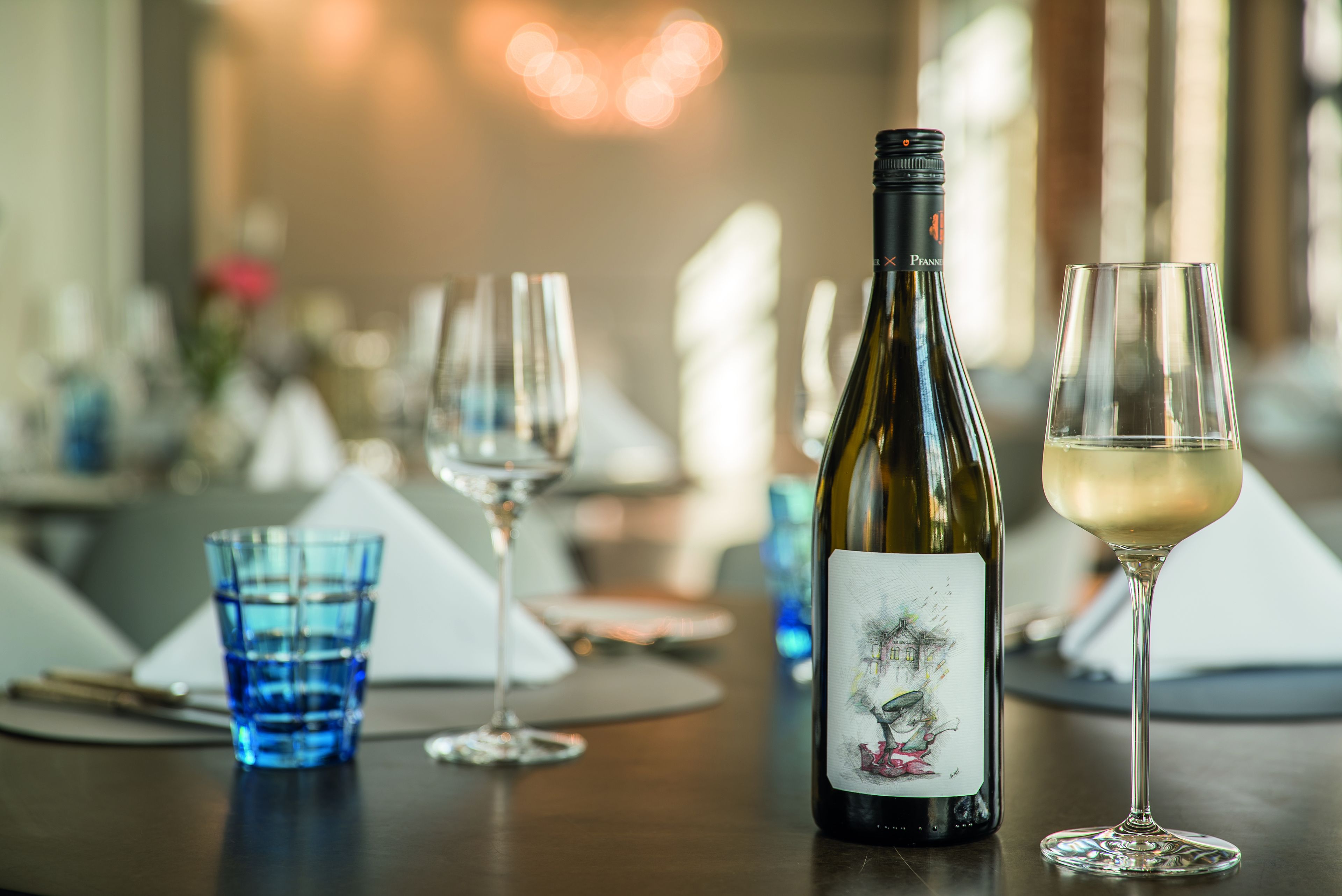 A dining table with a wine bottle and glasses.