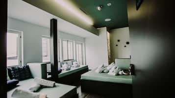 Ein modernes Hotelzimmer mit zwei Betten, einem großen Fenster, einer Deckenleuchte und einem wandmontierten Spiegel.