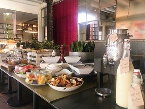 Una mesa de buffet con distintos alimentos y un dispensador de leche.