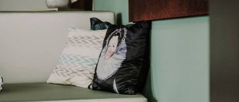 Una habitación moderna con una cama, estante en la pared y un cojín decorativo.