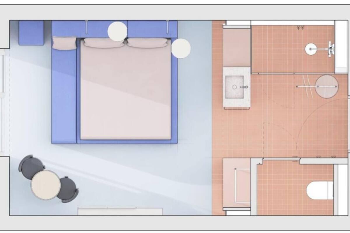A hotel room layout with a bed, a small sitting area with two chairs, a bathroom with a shower, toilet, and sink.