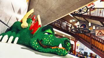 A LEGO dinosaur model in an indoor setting with a staircase and railing in the background.