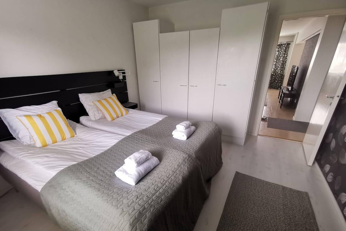A hotel room with two beds, a wardrobe, and a bathroom visible through an open door.