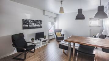 Een moderne woonkamer met een houten vloer, een zwarte leren fauteuil, een houten eettafel en hanglampen.