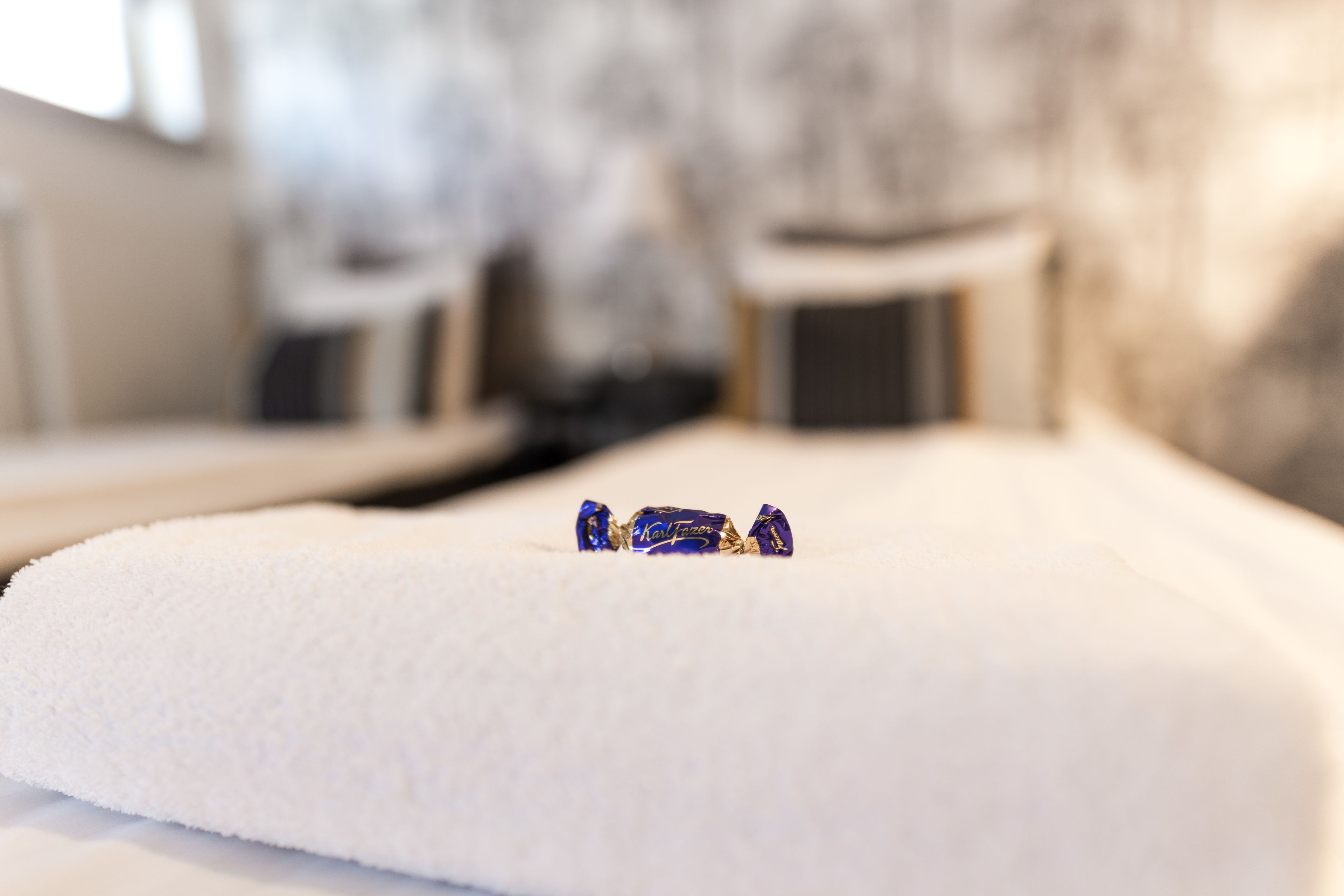 A bed with a white sheet and a small blue object on it.