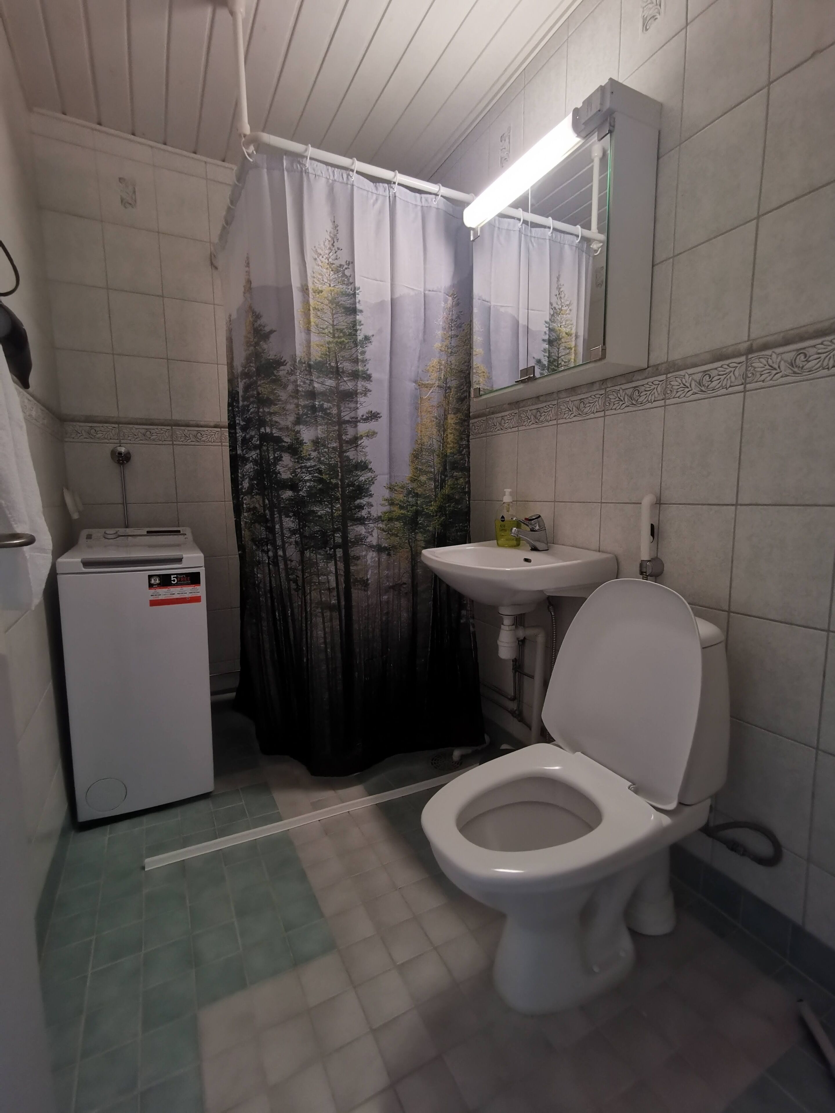 A small bathroom with a toilet, a sink, and a compact washing machine.