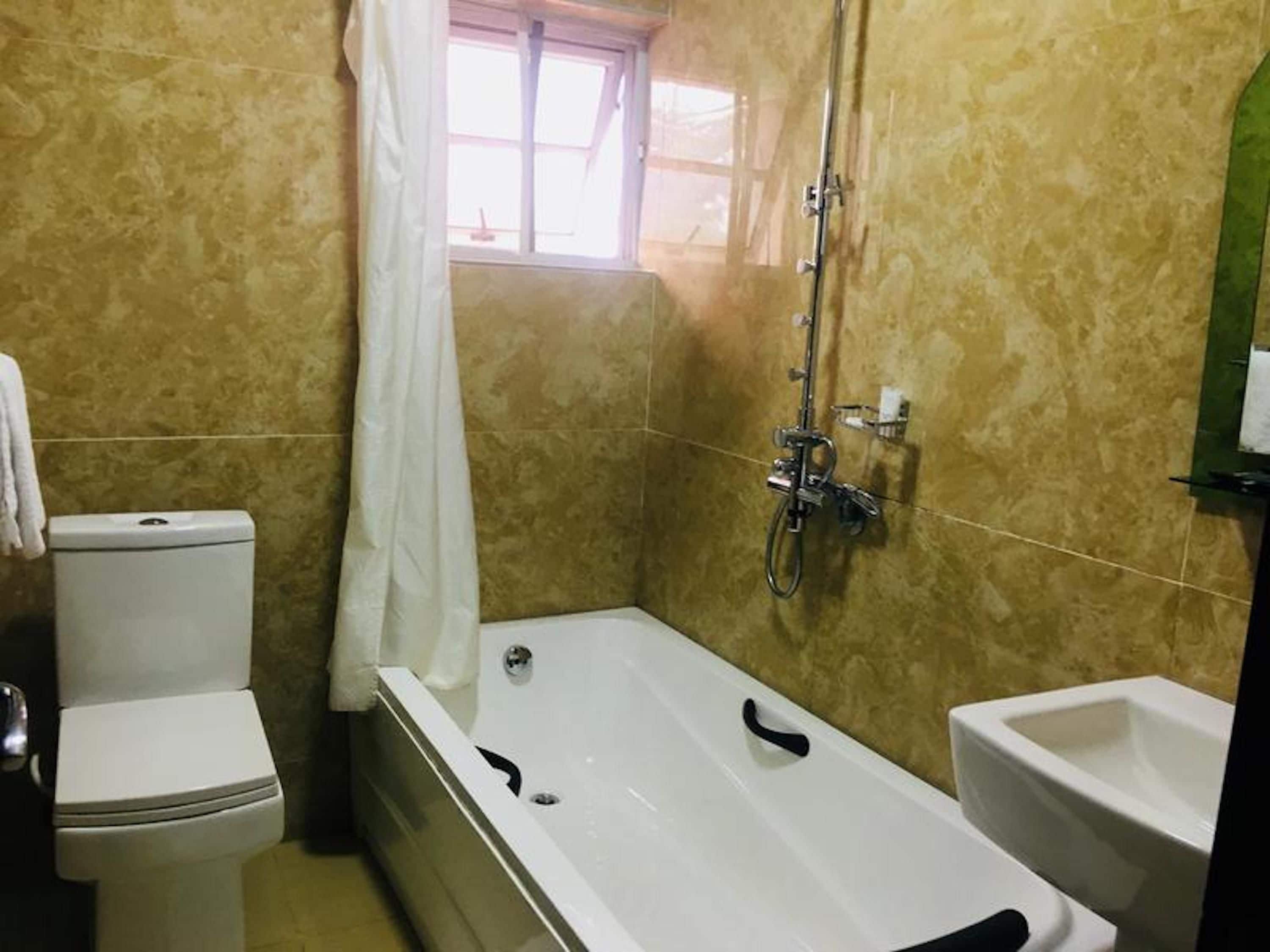 A bathroom with a bathtub, toilet, and bidet.