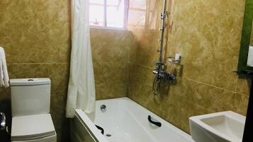 A bathroom with a bathtub, toilet, and bidet.