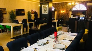 Ein Restaurant mit einem langen Tisch, der für eine Mahlzeit gedeckt ist, umgeben von Stühlen.