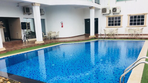 Ein rechteckiger Swimmingpool mit Fliesenbord und einer umlaufenden Liegefläche mit Kunstrasen und Stein.