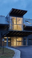 Uma casa moderna de dois andares com grandes janelas de vidro e uma área externa coberta.