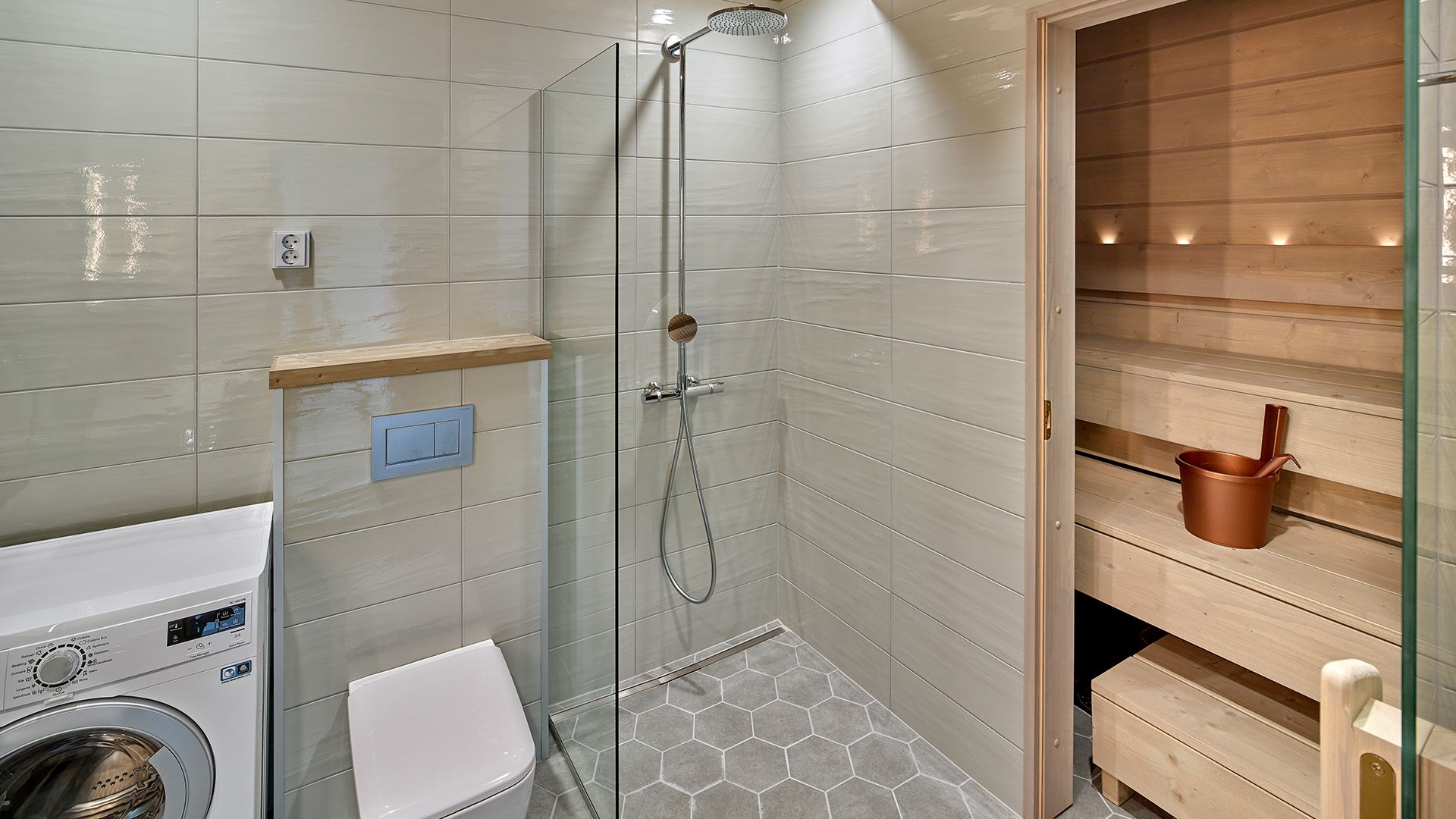 A modern bathroom with a glass-enclosed shower, a built-in washing machine, and a wooden sauna.