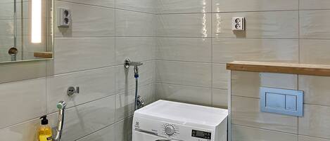 Une salle de bain moderne équipée d’un lave-linge, de toilettes et d’un lavabo.