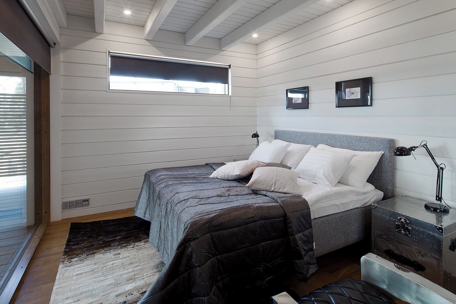 A bedroom with a bed, bedside tables, a window, and a suitcase.
