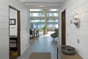 Um interior moderno com uma área de refeições, um espaço de estar e vista para um lago.