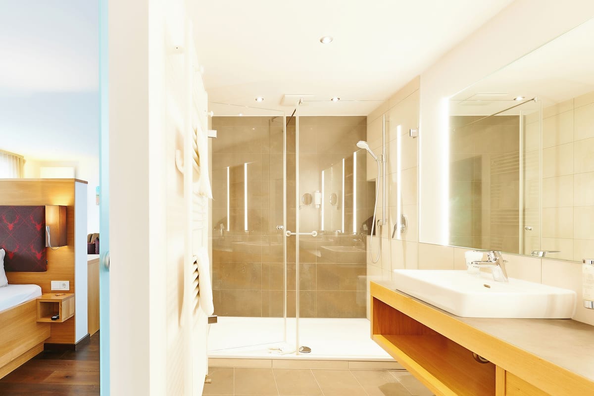 A modern hotel room with a bed, bedside table, and a large mirror.