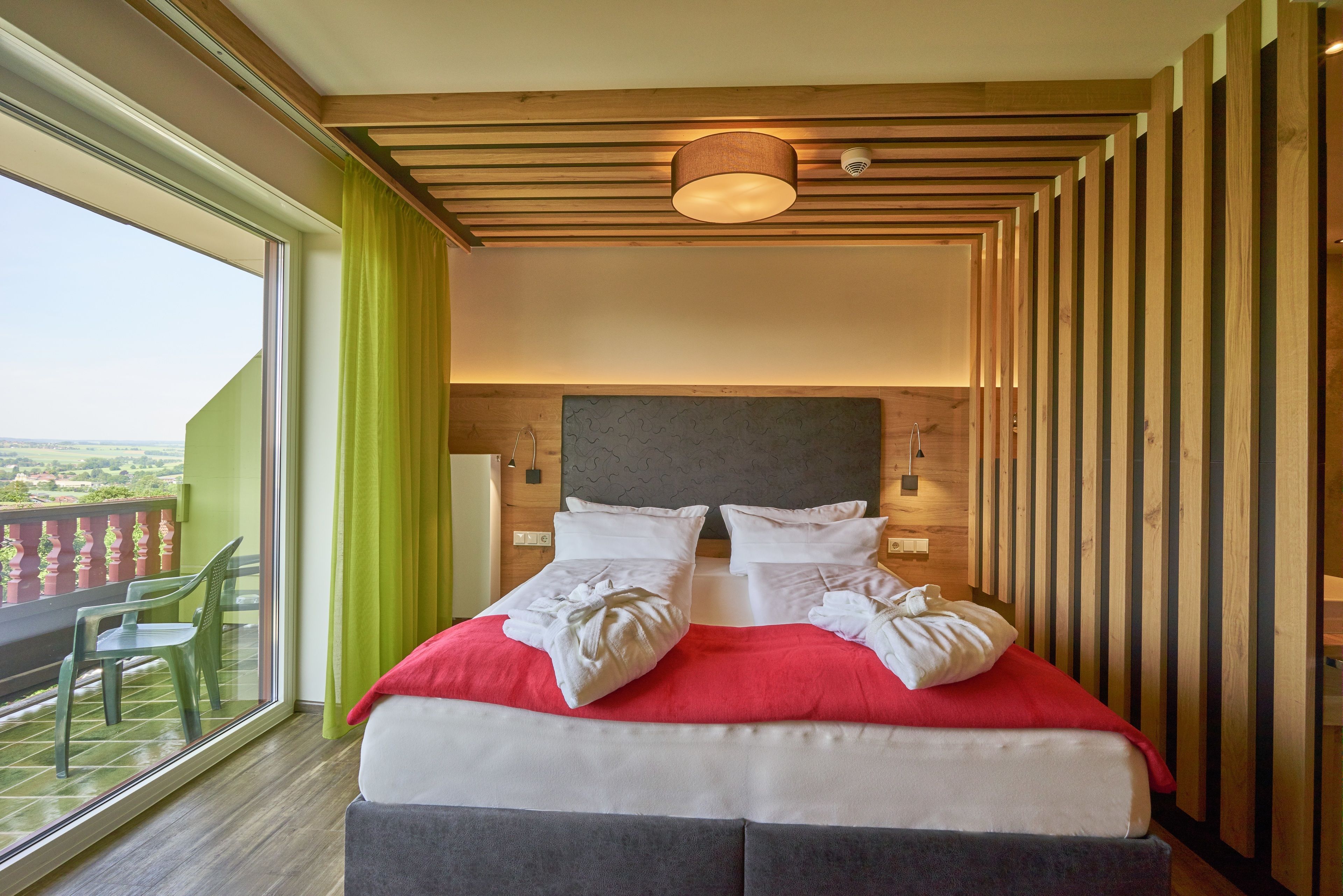 Un dormitorio con una cama grande, un balcón con vistas y paneles de madera en las paredes.