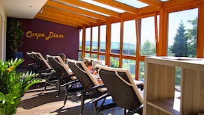 Una habitación soleada con sillas de mimbre, techo de madera y ventanas amplias con vistas al exterior.