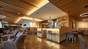 Un restaurante moderno con techo de madera, zona de bar, disposición de mesas y un ciervo decorativo en la pared.