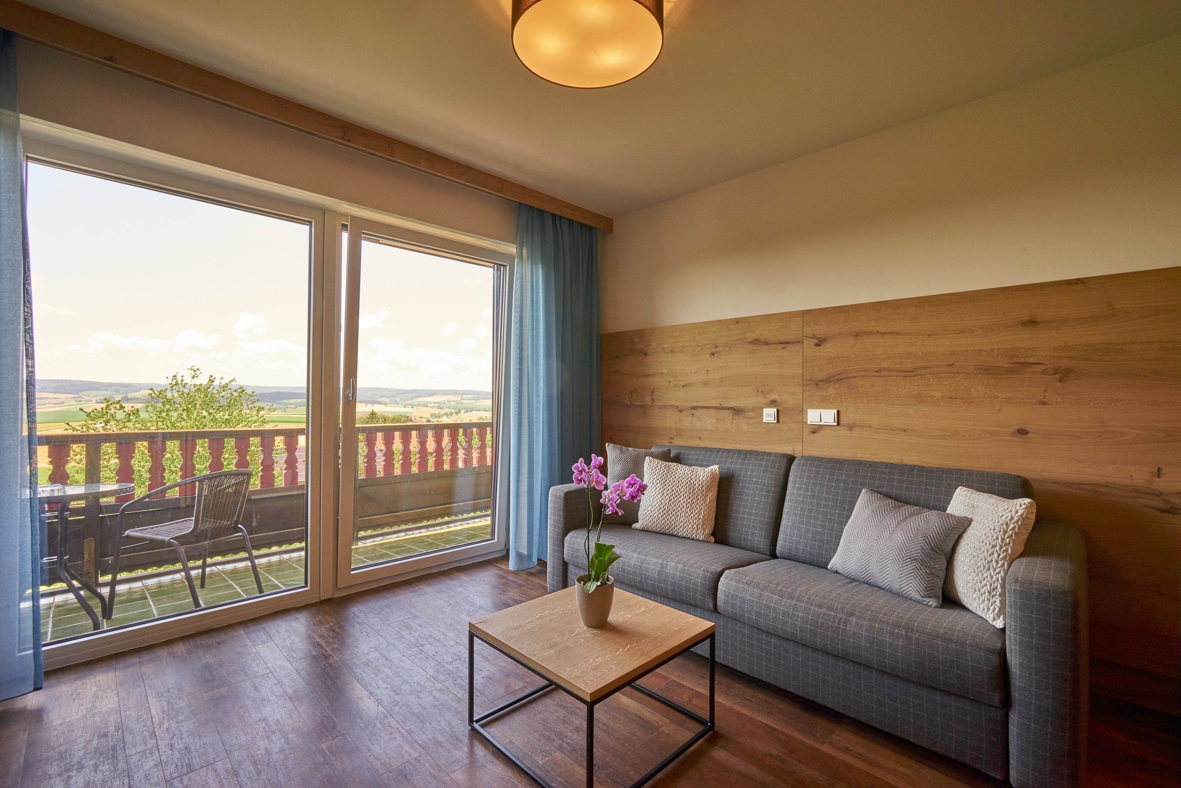 A living room with a sofa, a coffee table, and a view of the outdoors through large sliding glass doors.