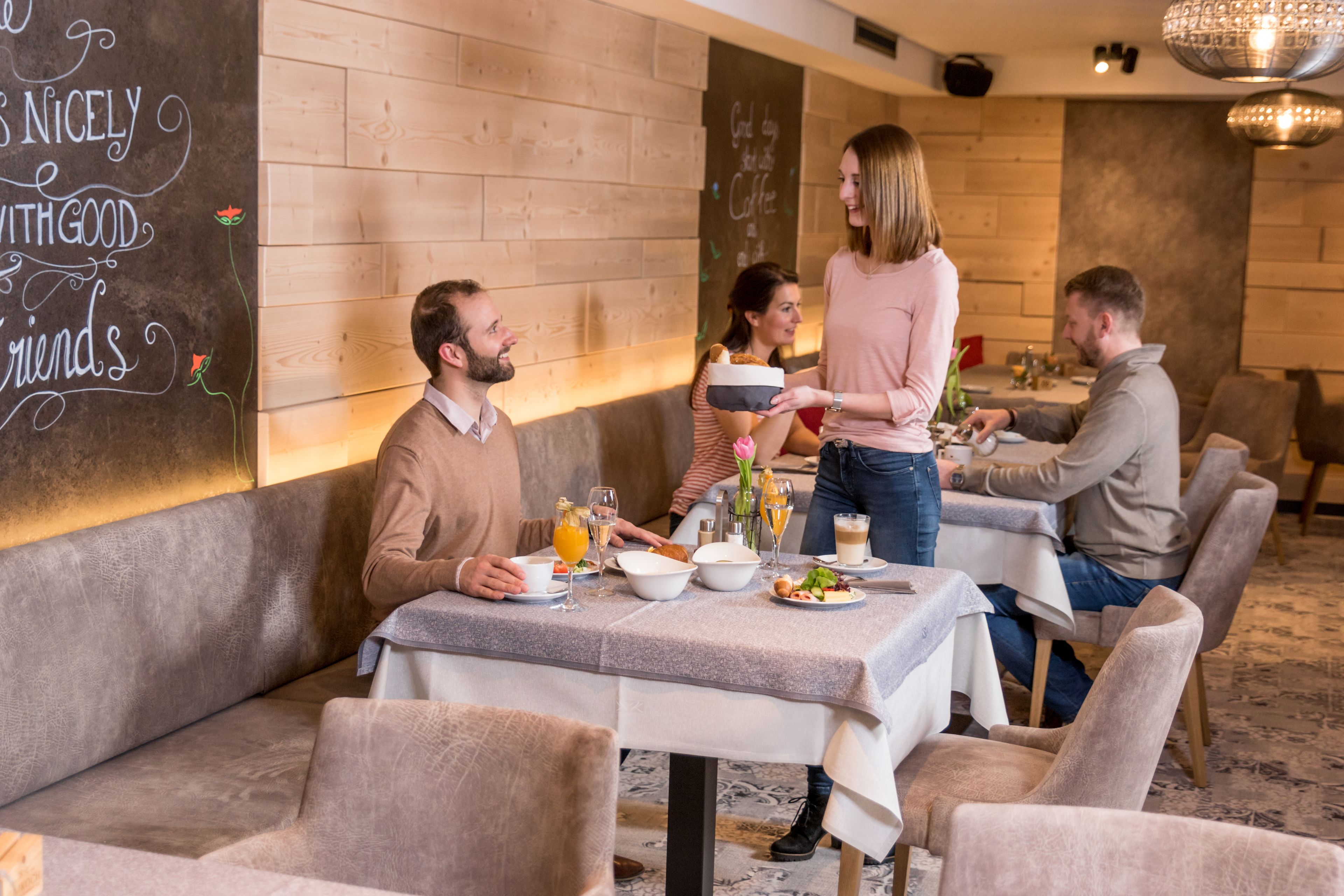 Un restaurant aux murs en bois, un tableau noir avec des inscriptions et une table dressée pour le repas.