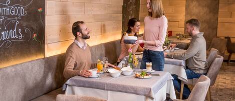 Un restaurant aux murs en bois, un tableau noir avec des inscriptions et une table dressée pour le repas.