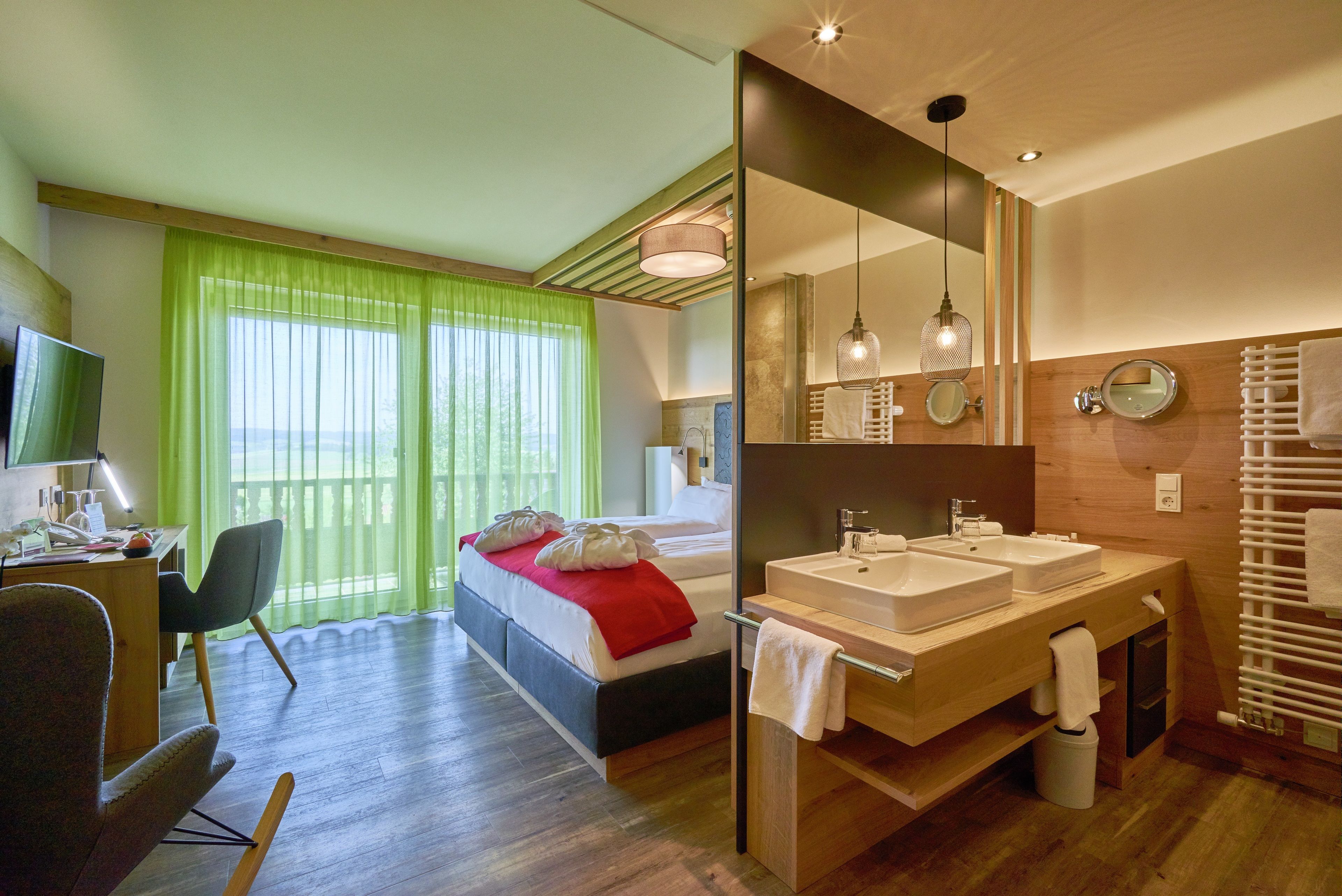 Une chambre d’hôtel moderne équipée d’un lit, de deux lavabos, d’un miroir et d’un bureau avec une chaise.