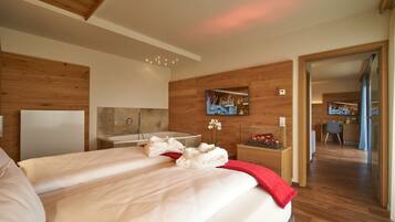 Una habitación de hotel moderna con una cama grande, paneles de madera, un baño con bañera y un escritorio pequeño con silla.