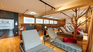Relax in a serene spa room with a large window, massage chairs, and a unique tree sculpture.