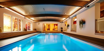 Una amplia piscina cubierta con techo de madera y paredes decoradas con obras de arte.