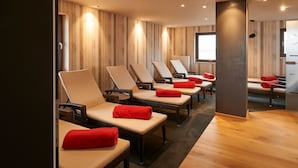 Un cuarto de spa con varias sillas de masaje, suelo de madera y techo perforado.