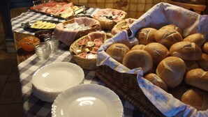 A buffet table with various food items, including bread and baskets of condiments. - Landgasthof Waldrast (Voehrenbach)