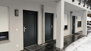 A modern building with three dark-colored doors, each with a small window above. - Landgasthof Waldrast (Voehrenbach)