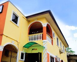 Un edificio amarillo con un balcón, un toldo verde y un letrero que dice "RECEPTION".