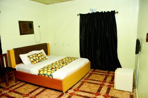 Una habitación con cama, una silla, un calentador y una cortina.