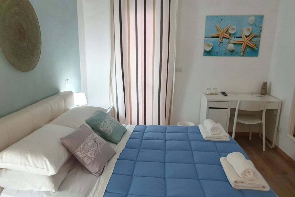 Un dormitori amb un llit, almoines, un escriptori i una cadira.