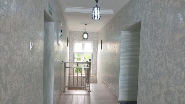 A hallway with textured walls, a metal railing, and a hanging light fixture. - De Maria Inn (Lagos)
