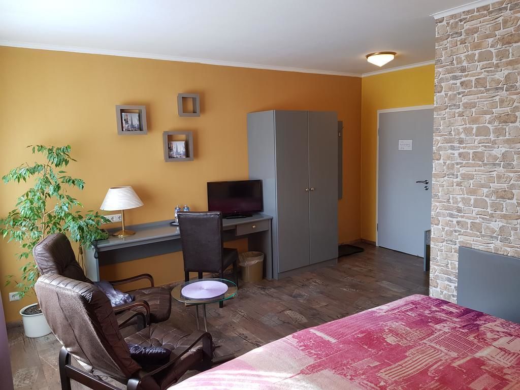 Habitació amb un llit, escriptori amb ordinador, cadira, làmpada i una planta.