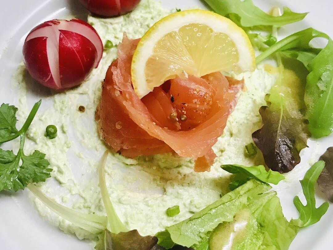 A salad with smoked salmon, lemon, and greens.