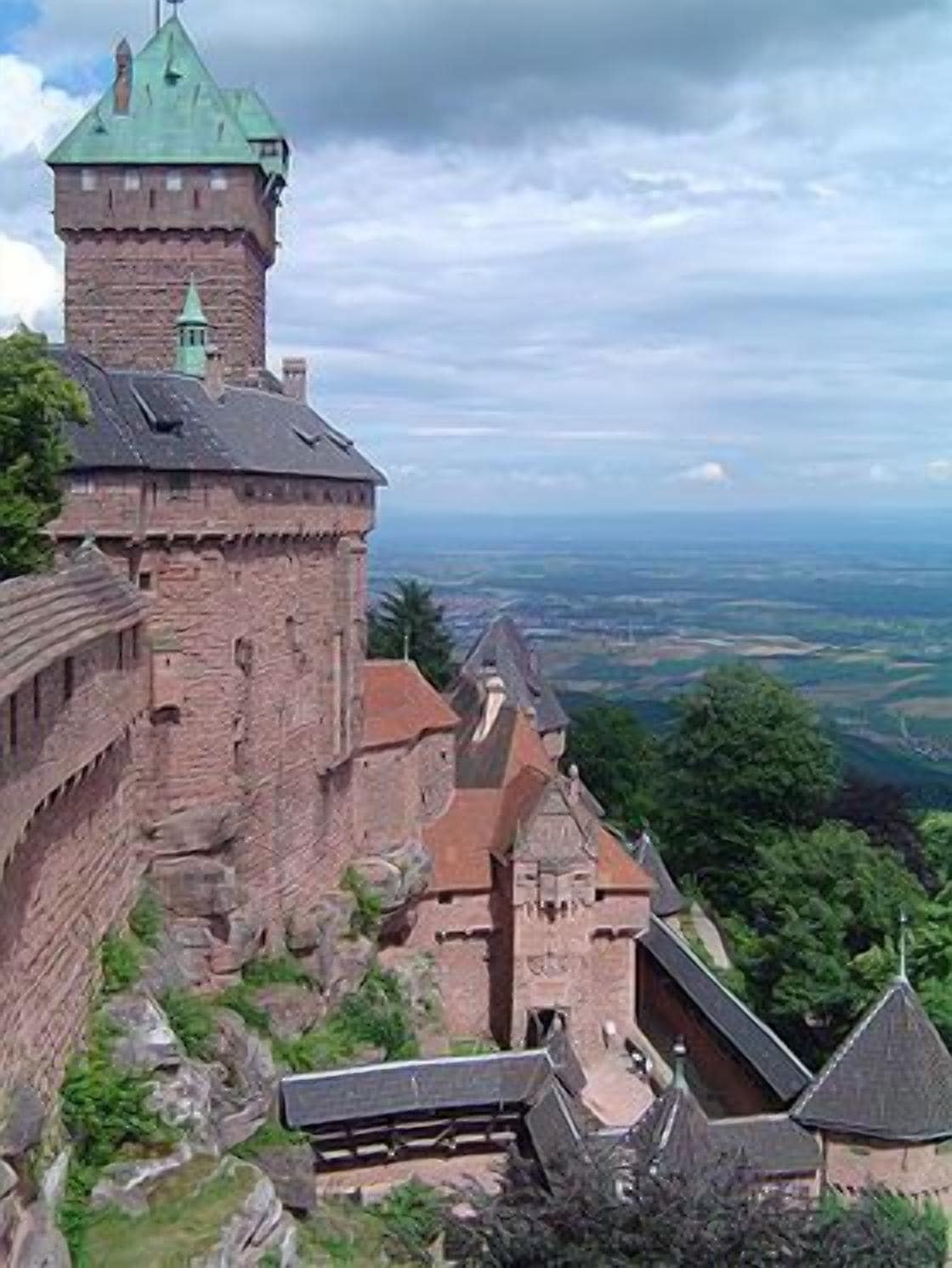 A historic castle with a prominent tower, surrounded by lush greenery and offering expansive views of the landscape.
