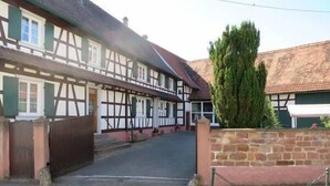 Ein traditionelles Fachwerkhäuschen mit einem verschlossenen Eingang, einer Steinmauer und einem gepflasterten Zugang.
