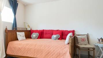 Une chambre à coucher avec un lit en bois, des oreillers rouges et une couvre-lit matelassée de couleur pêche.