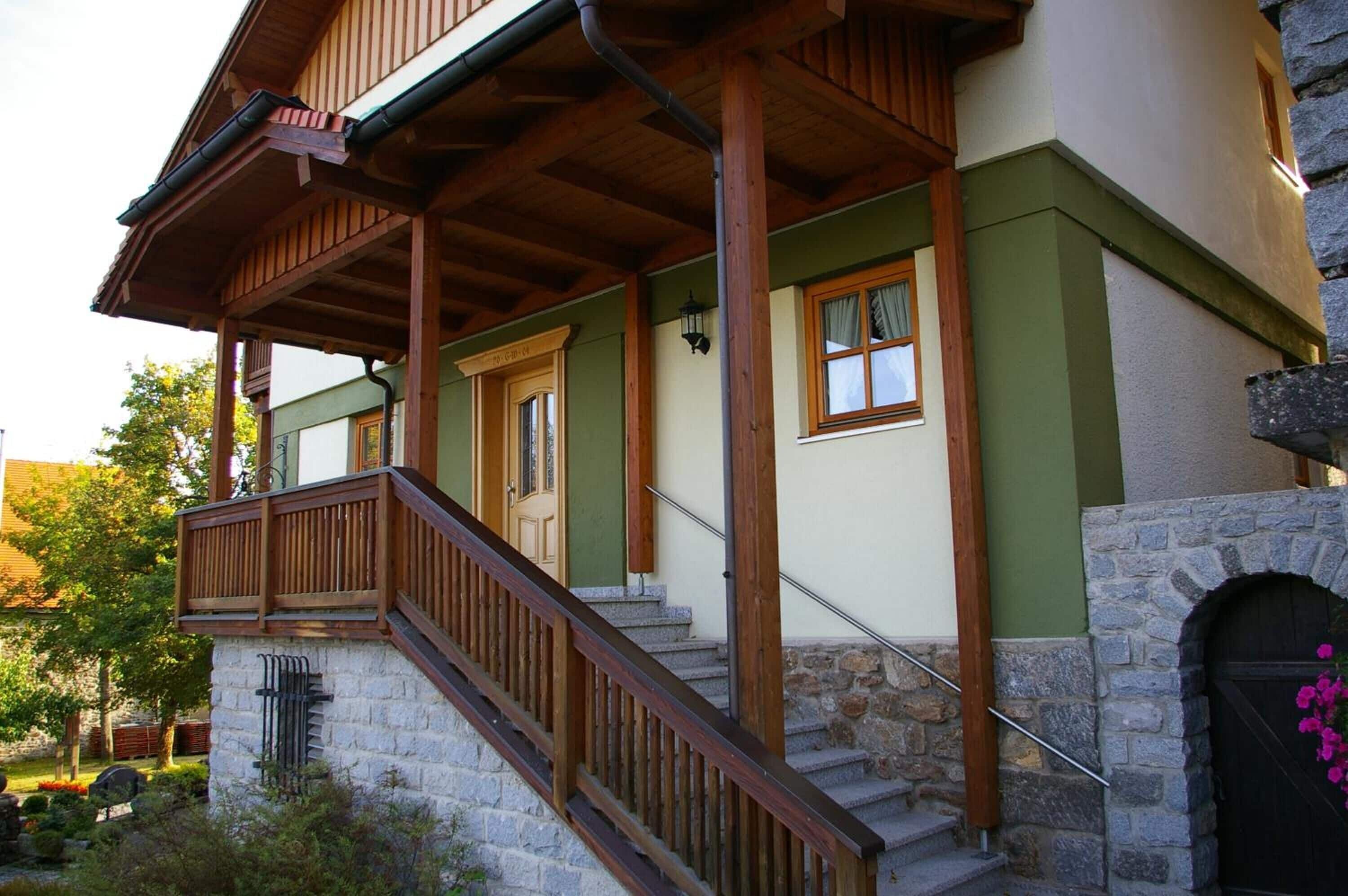 A two-story building with a wooden balcony, stone steps, and a stone archway.