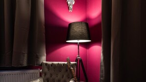 Une pièce comprenant un fauteuil à capitons, une guitare, une lampe et un crâne accroché au mur.
